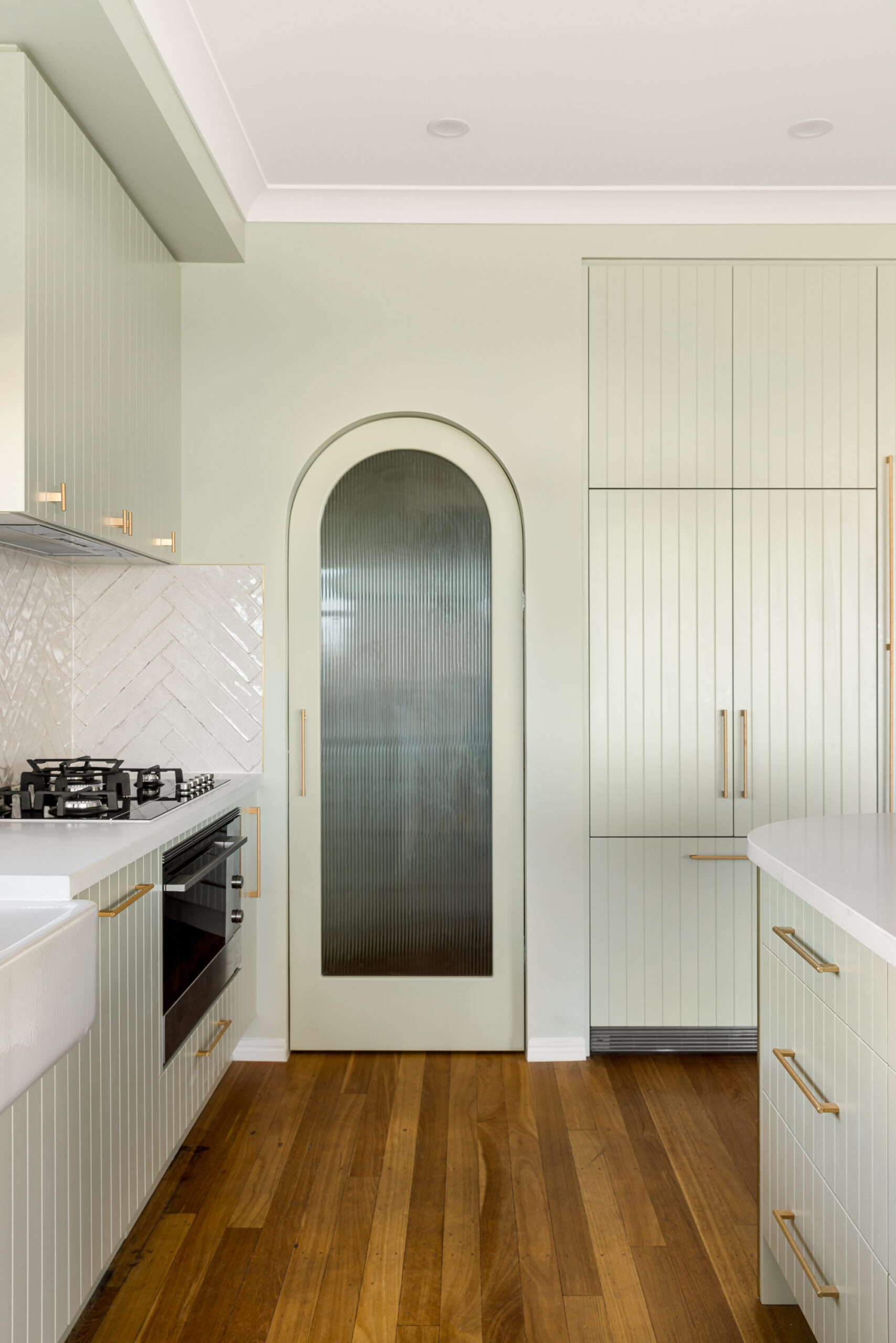 A modern kitchen after renovation with an arched door filled with textured glass