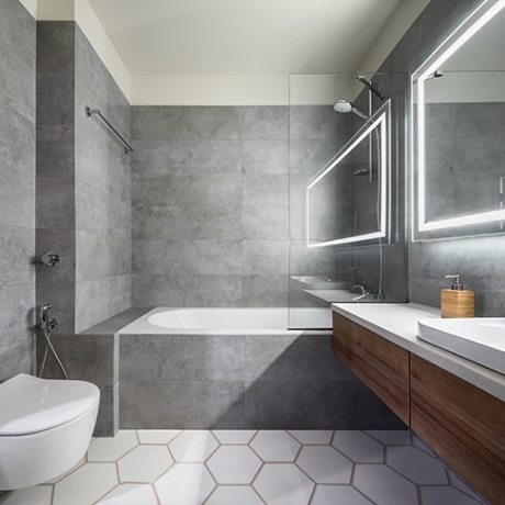 Grey bathroom wall tiles in a bathroom with a white bath, sink and toilet.
