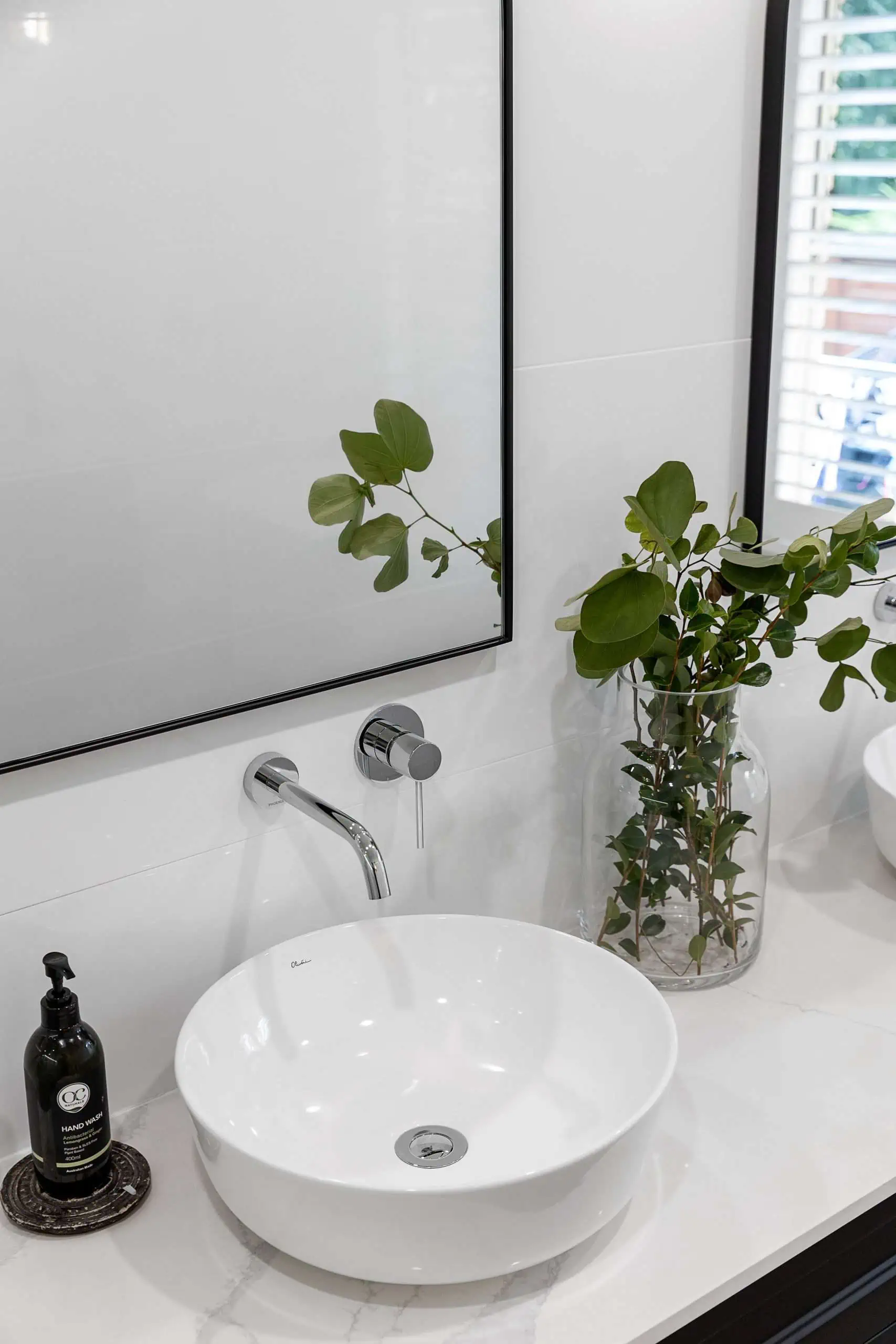Black framed mirrors above white sinks in a modern bathroom