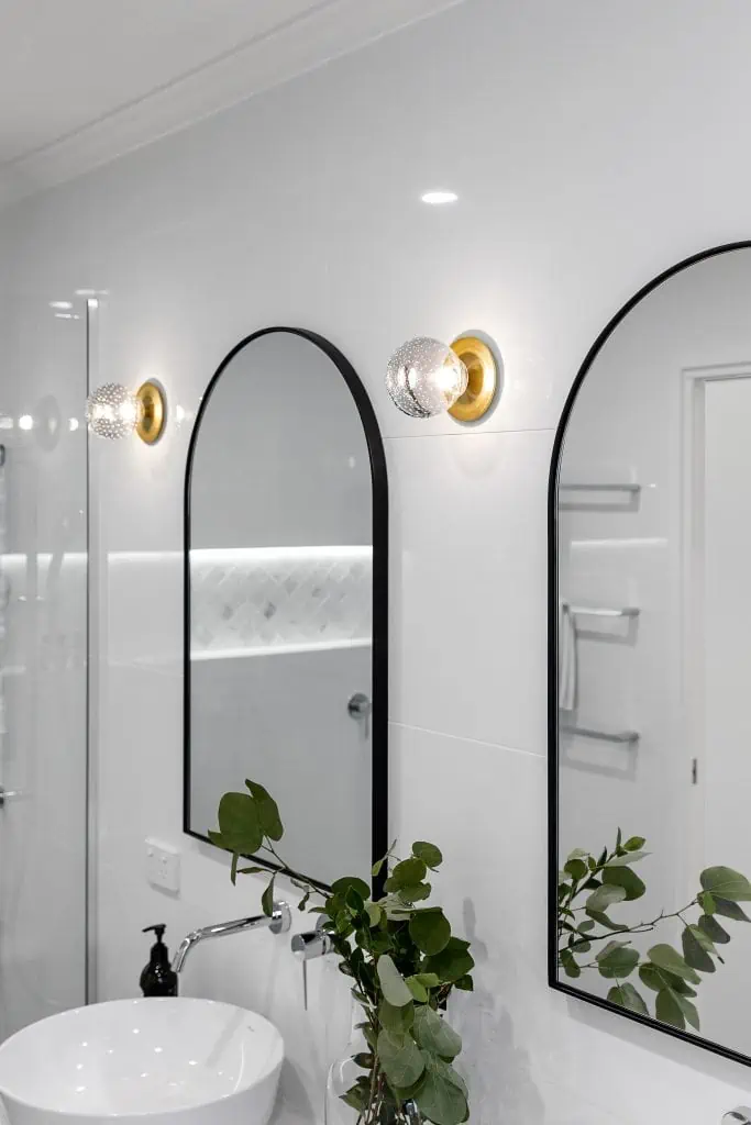 Black framed arch mirrors in a white and black bathroom