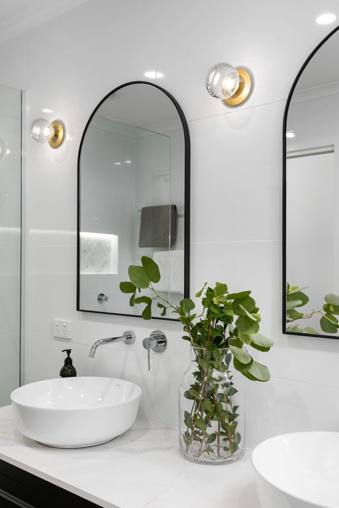 Two arch mirrors with black frame above white sinks