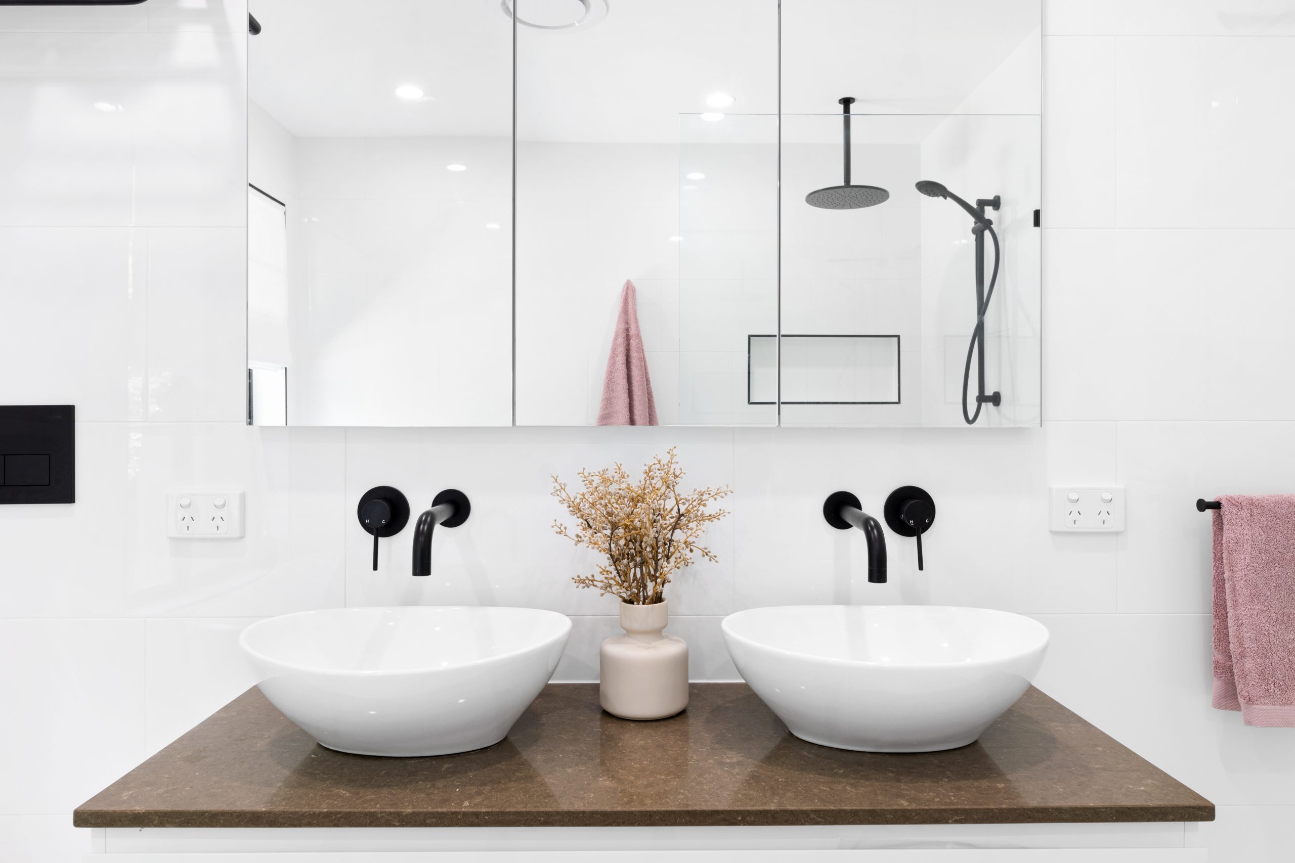 White bathroom with black details featuring two sinks and mirrored wall unit
