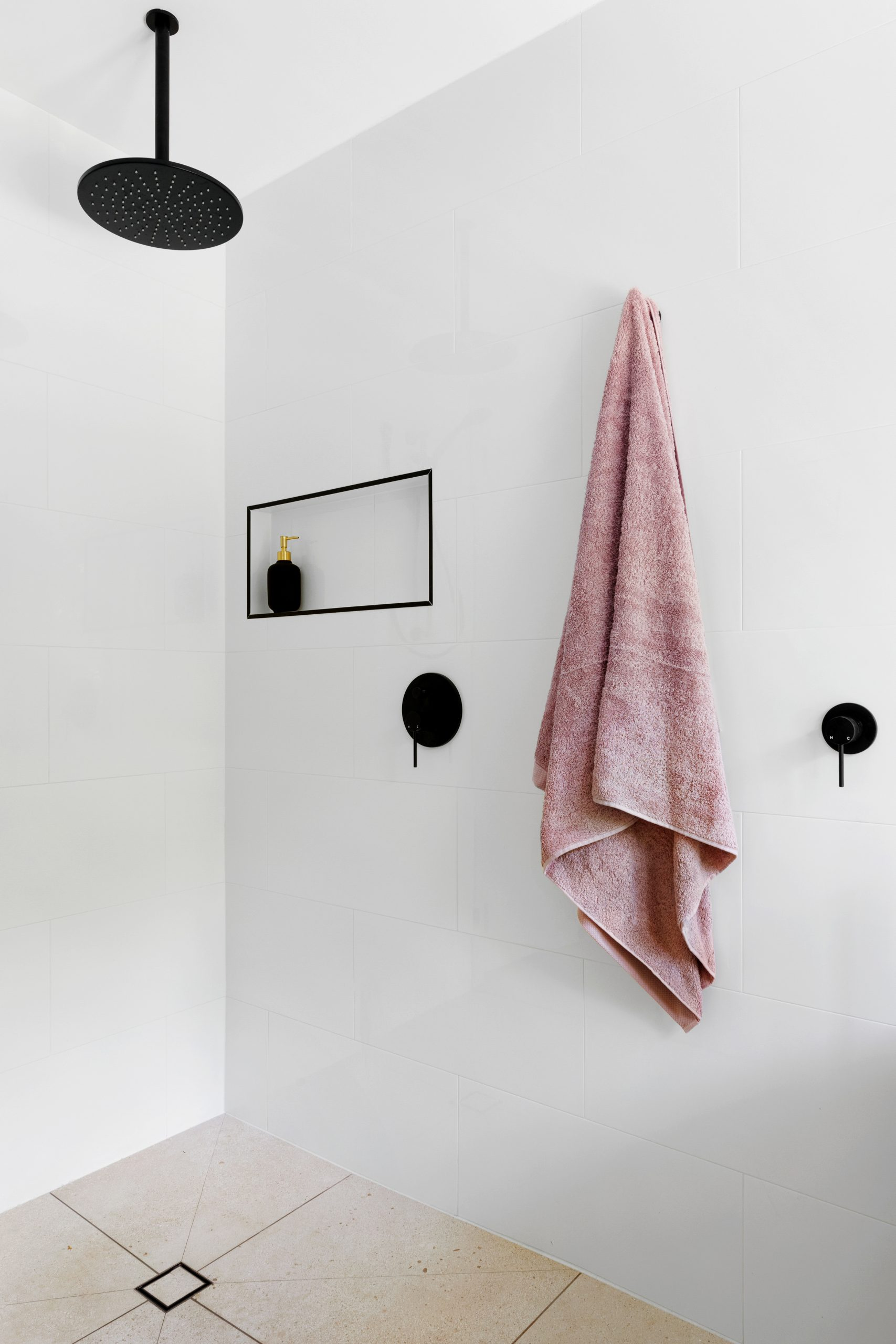 White bathroom with black details and a pink towel