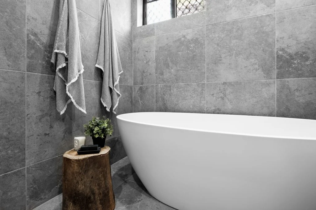 Grey bathroom tiles with white bath