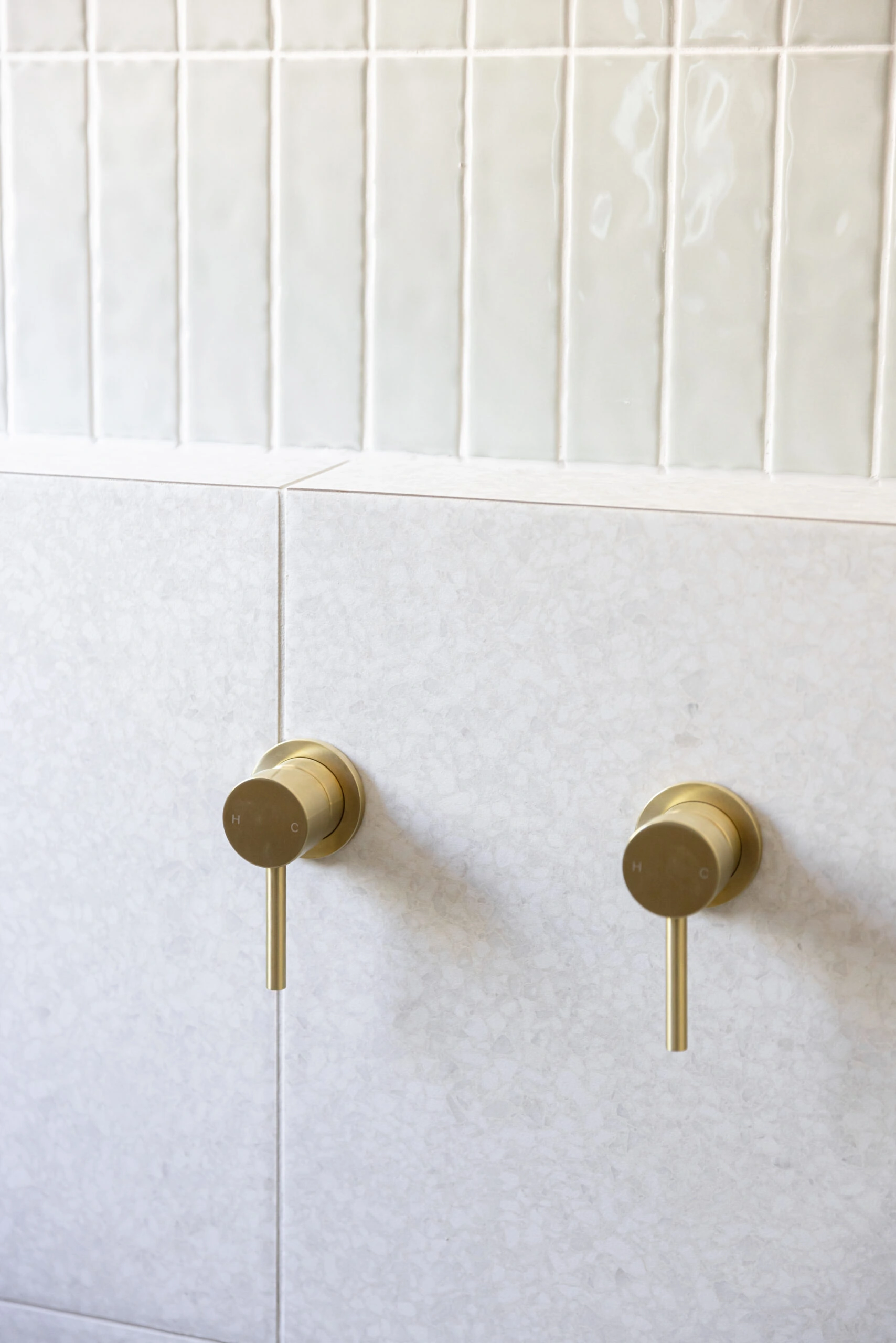 Gold taps on light tiles showing the details of a bathroom renovation