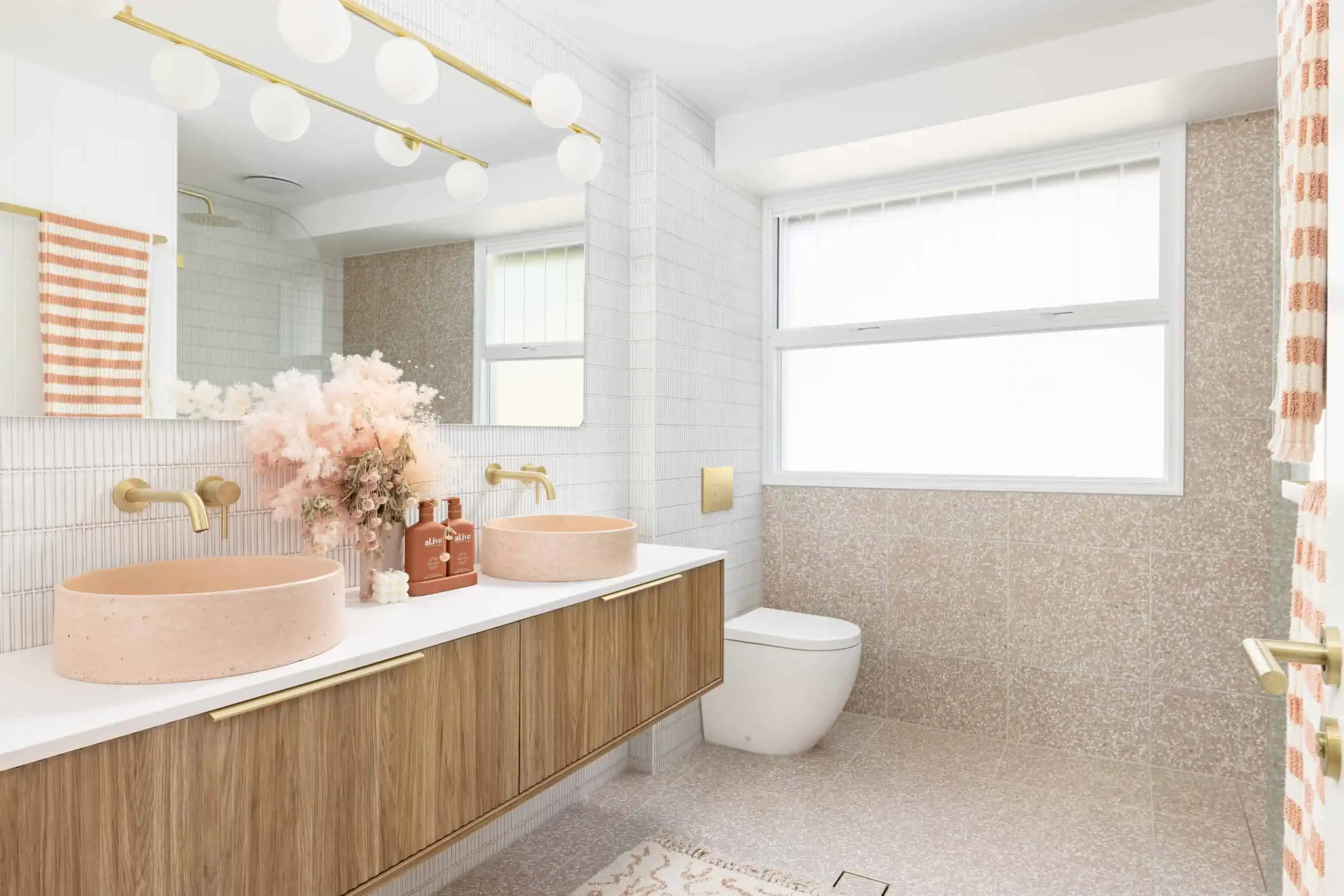Wide shot of a bathroom renovation after shot with pink granite, new vanity and pink and gold accessories.