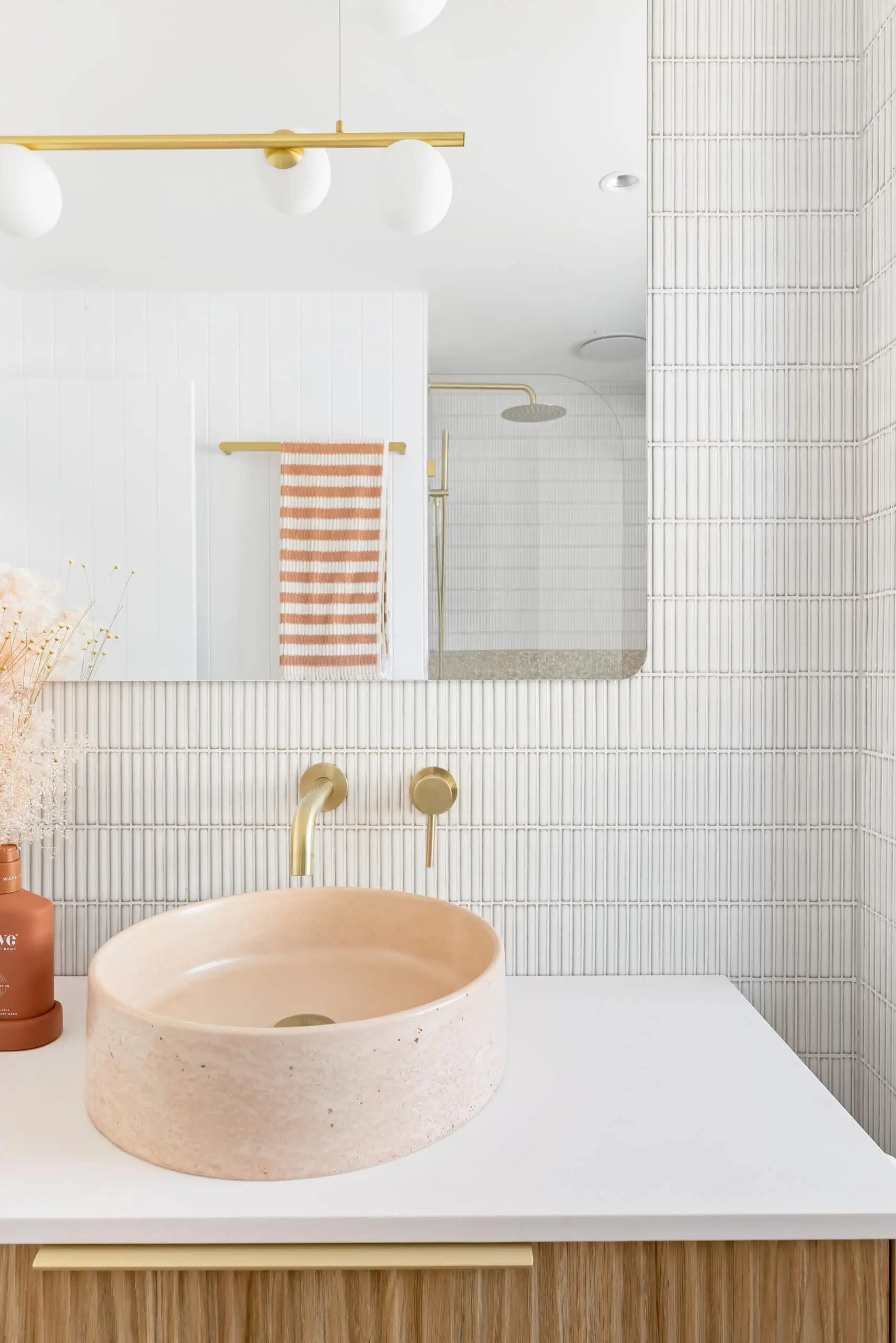 blush pink, gold and white aesthetic in a new bathroom renovation. Pink sink, gold taps and large mirror featured.