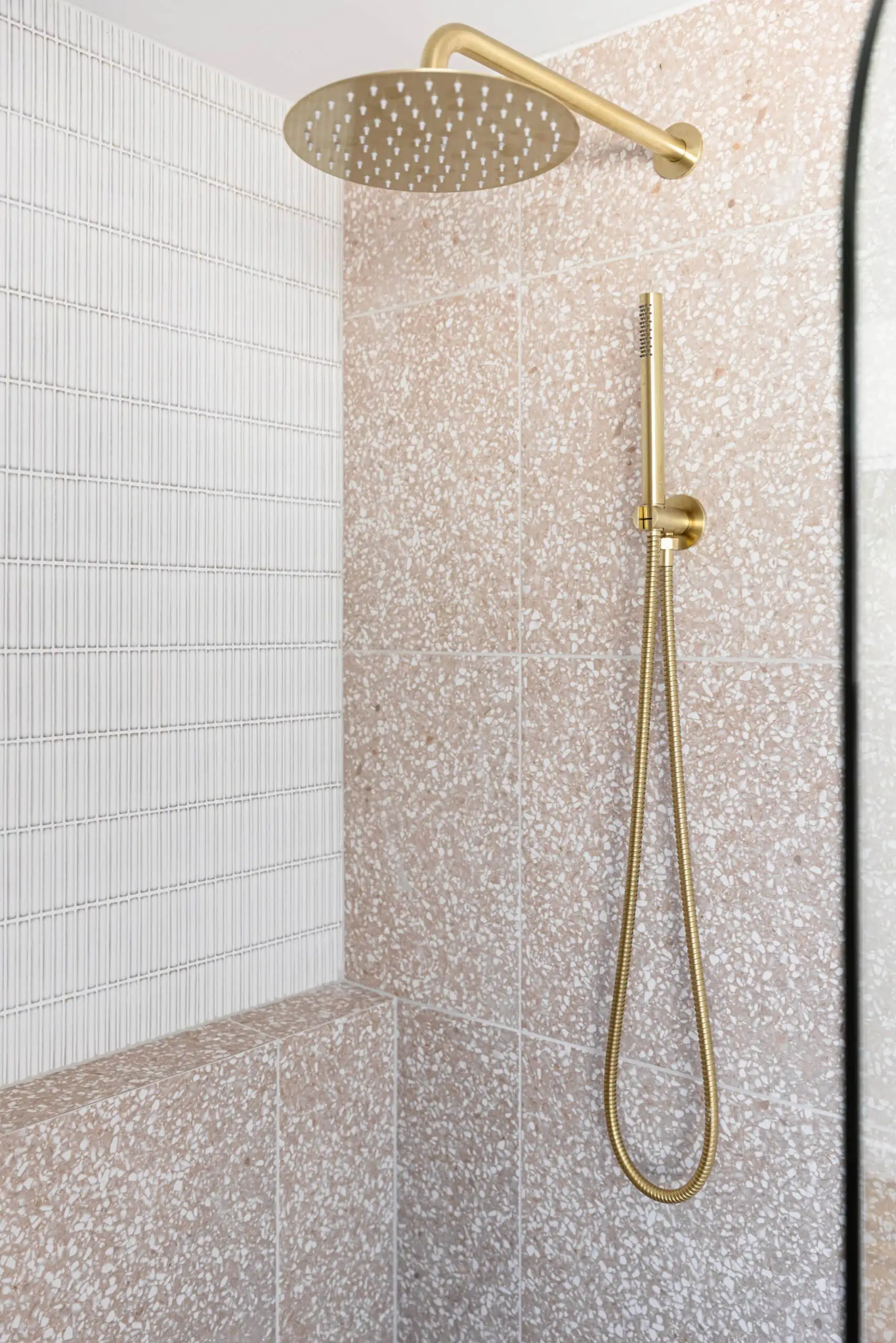 Gold shower accessories and pink granite tiles.