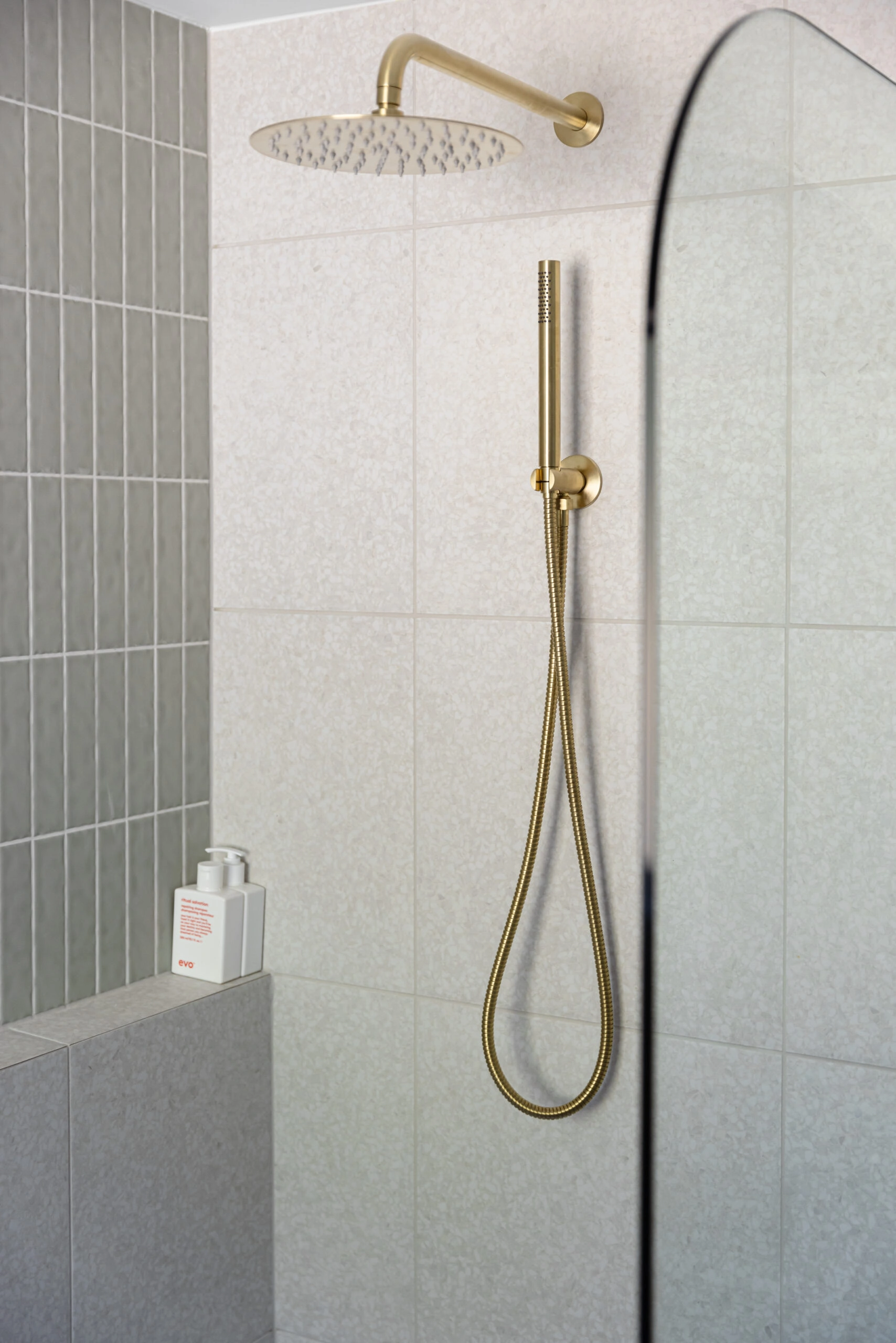 Gold shower accents on light bathroom tiles