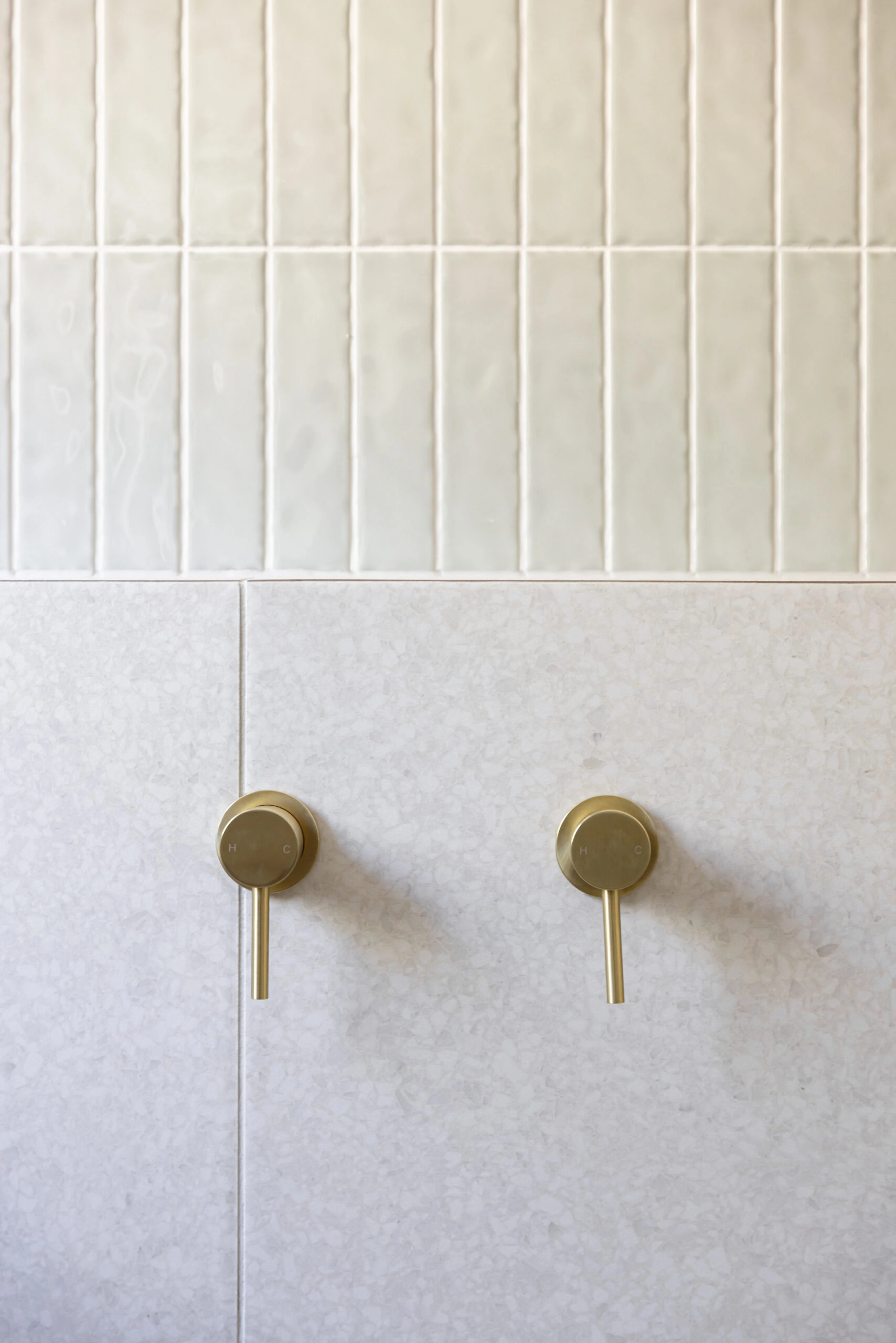 Gold taps on light bathroom tiles