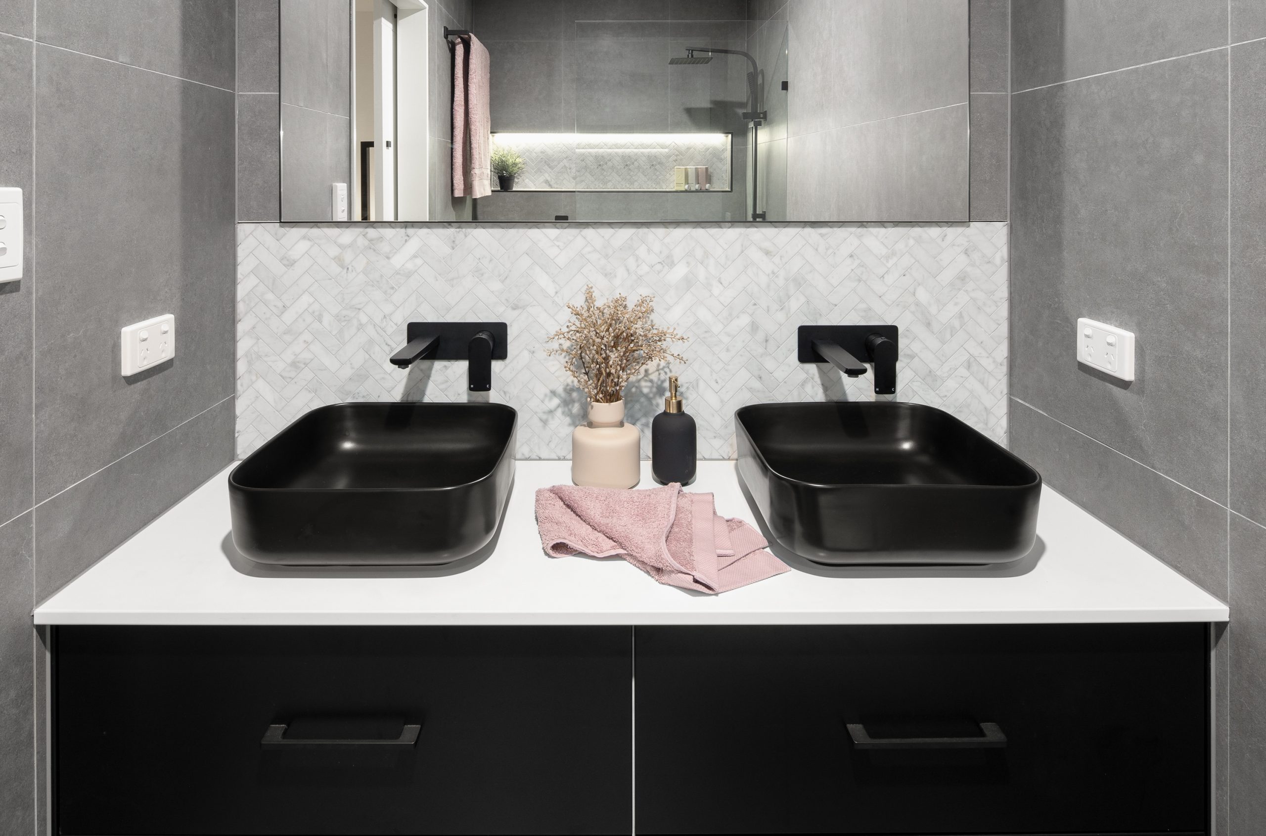 Two black sinks, white counter top and black draws in a modern bathroom