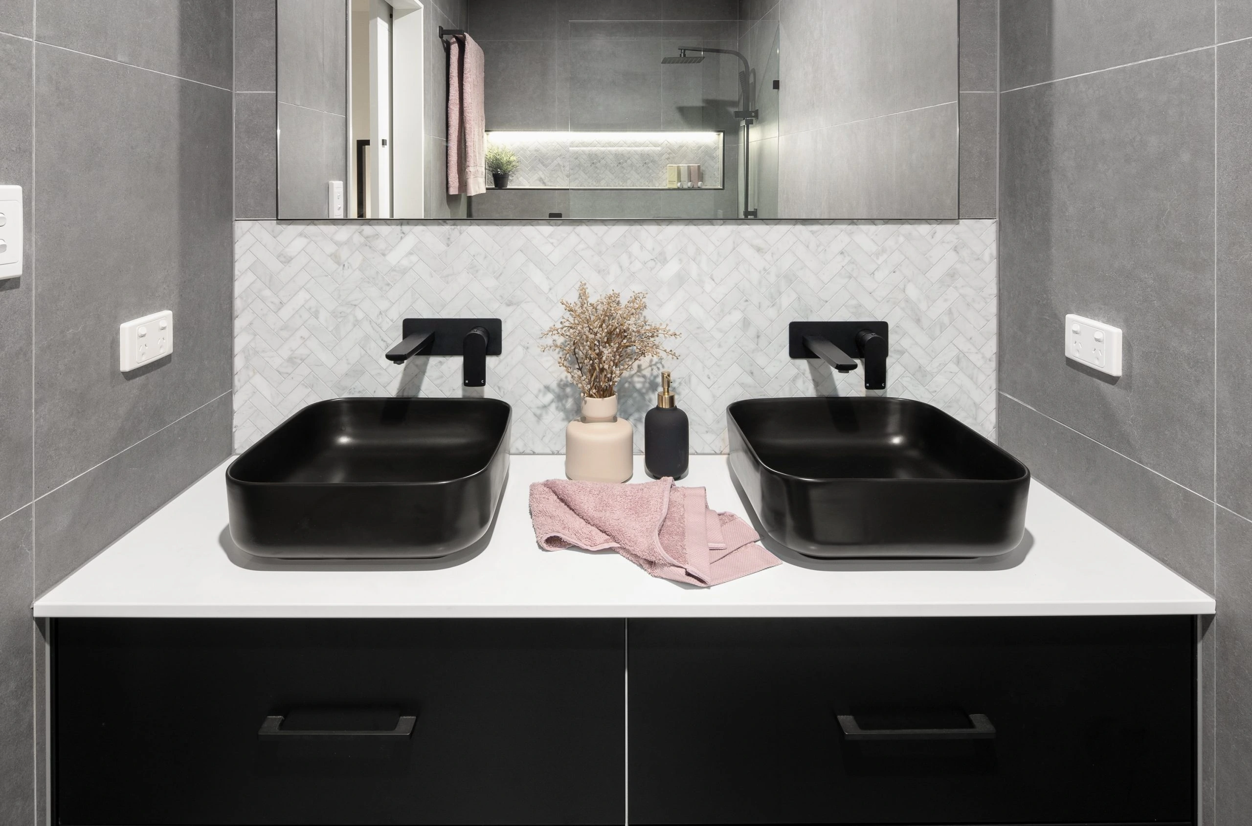 Two black sinks, white counter top and black draws in a modern bathroom