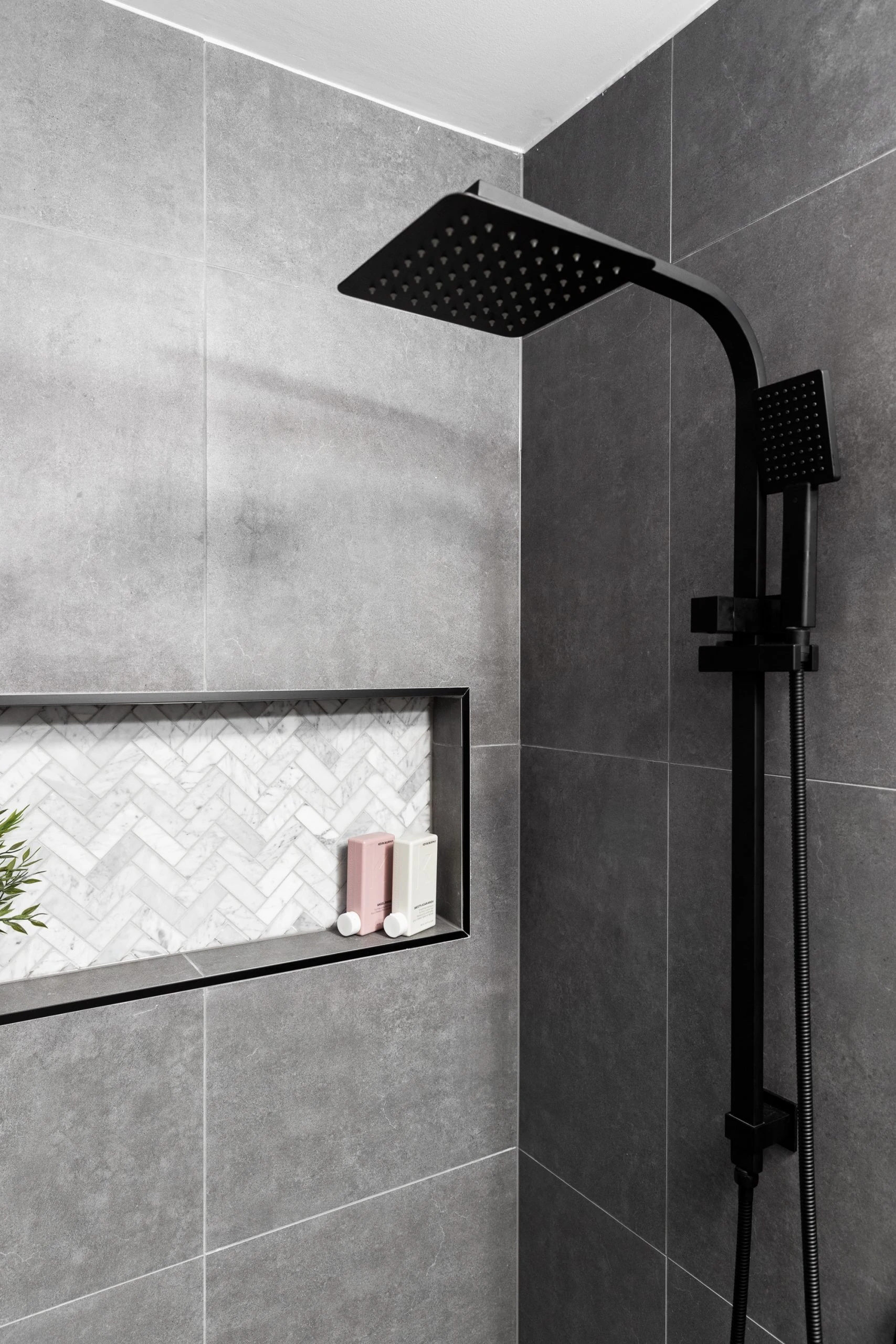Dark grey bathroom with black details featuring shower and wall niche