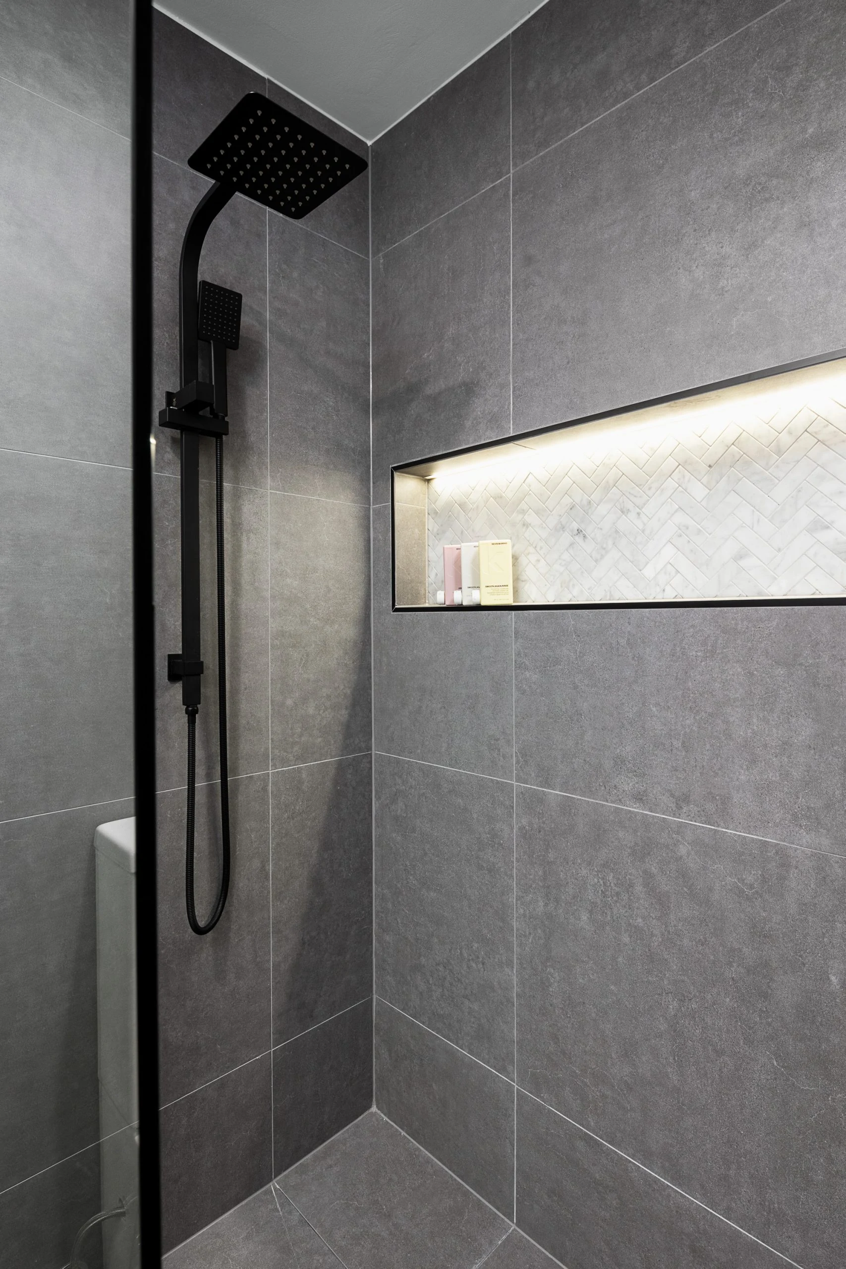 Grey bathroom with black details featuring a shower and wall niche