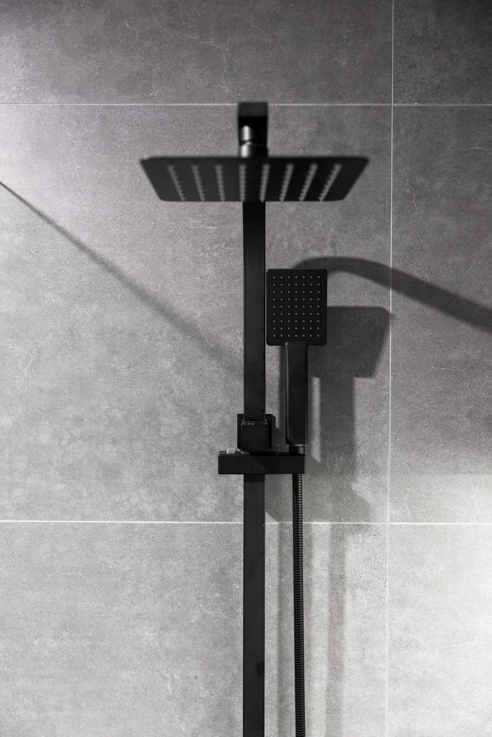 Matte black shower unit on large dark grey tiles