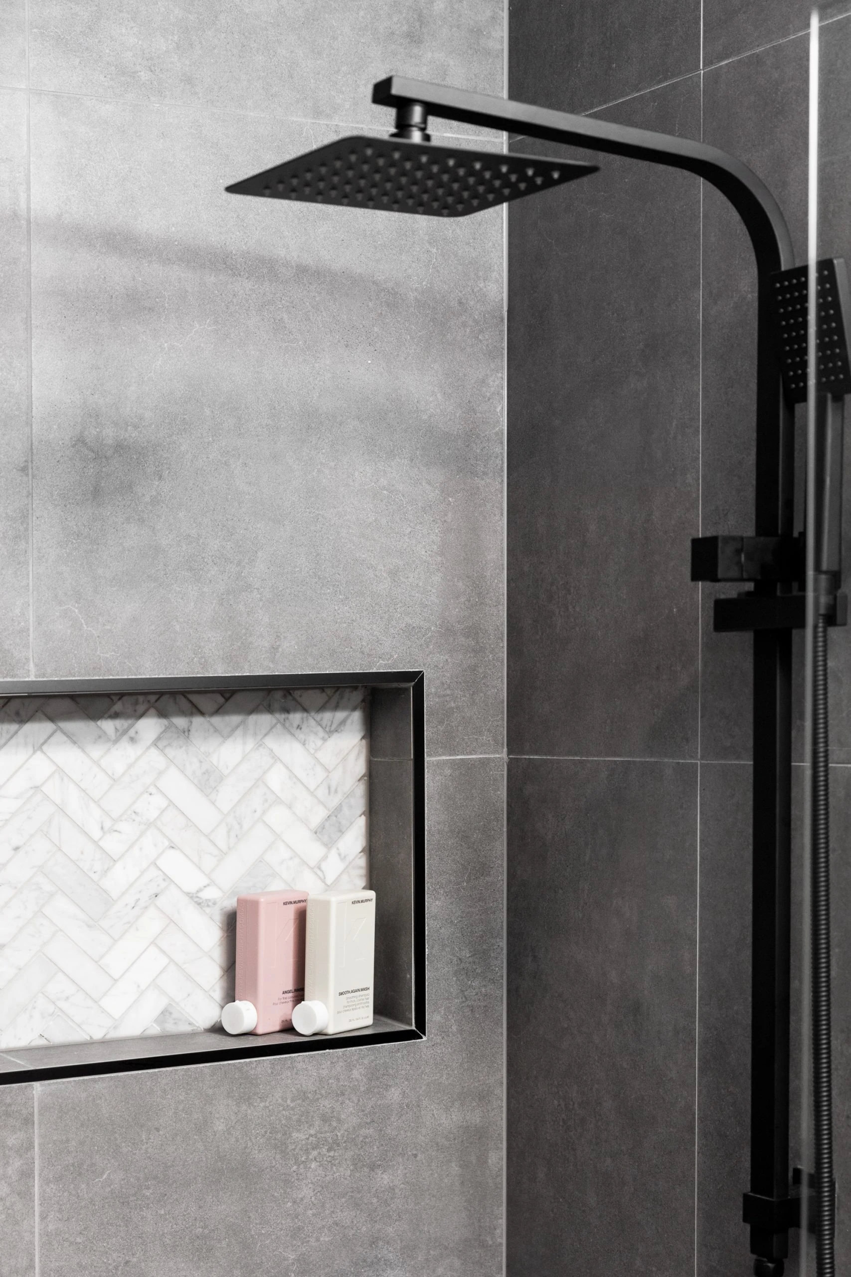 Dark grey bathroom with black details featuring a shower and wall niche