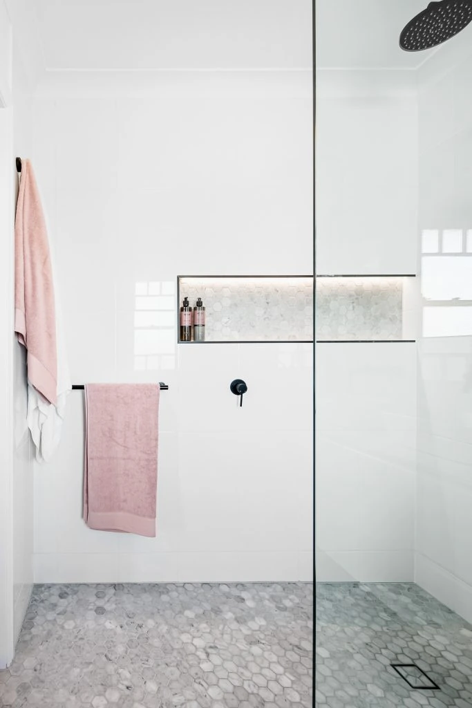 White bathroom with black details and a pink towels