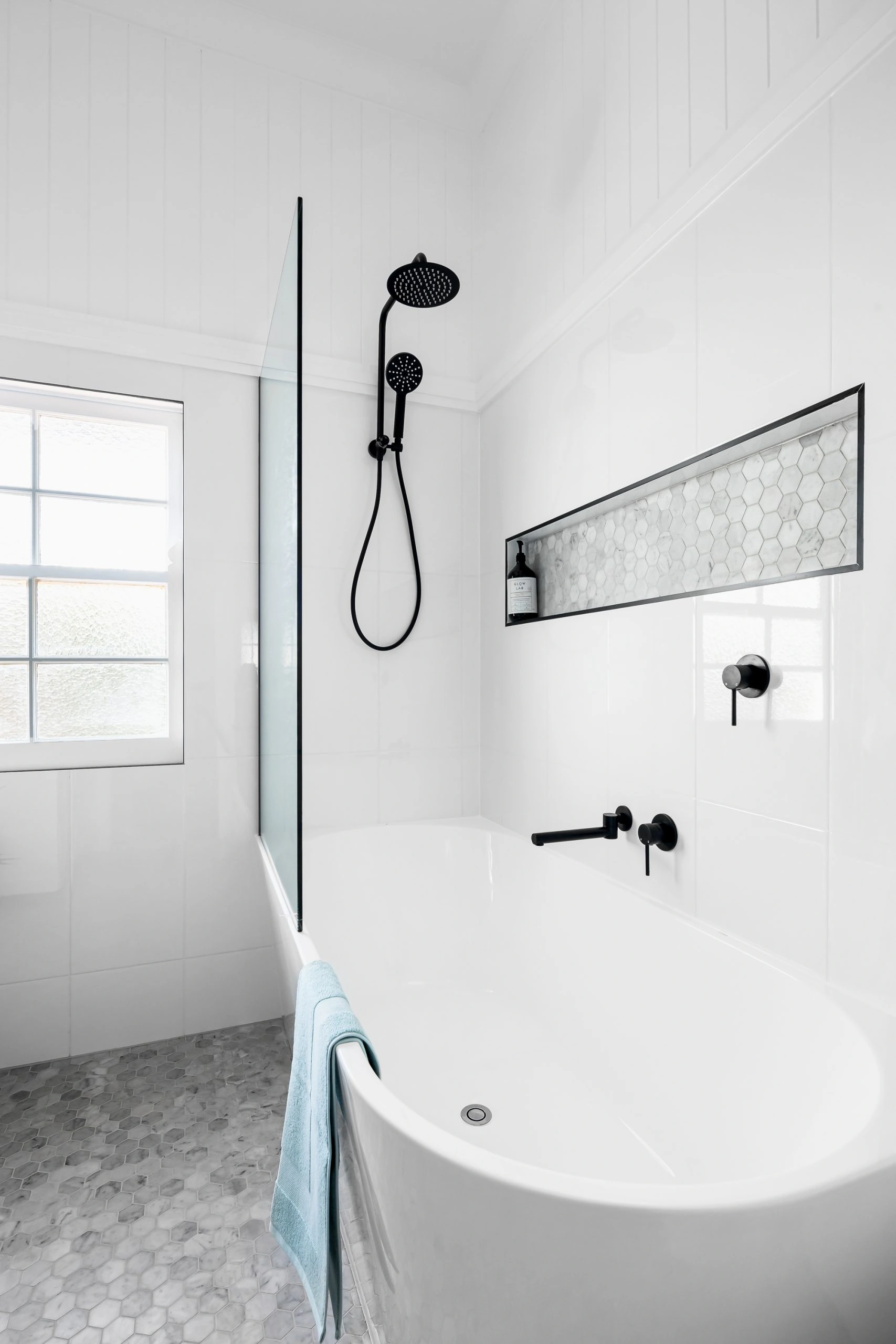 White bathroom with black details, featuring a large bath