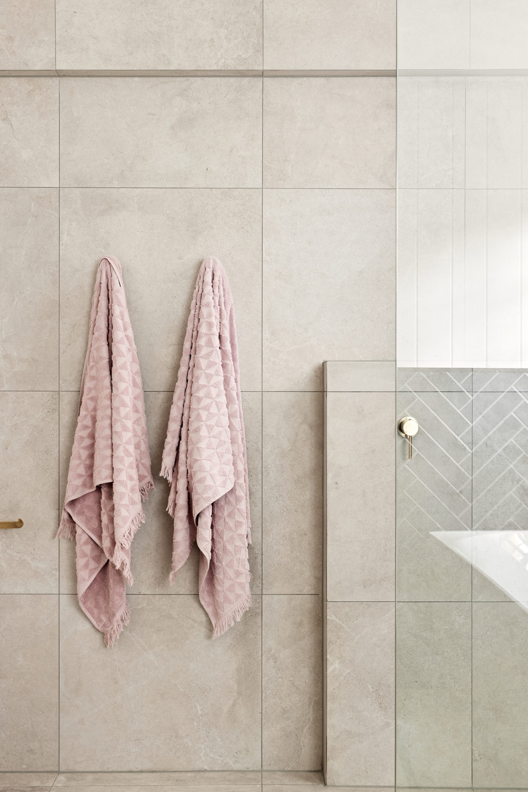 Large natural coloured bathroom tiles with pink towels hanging
