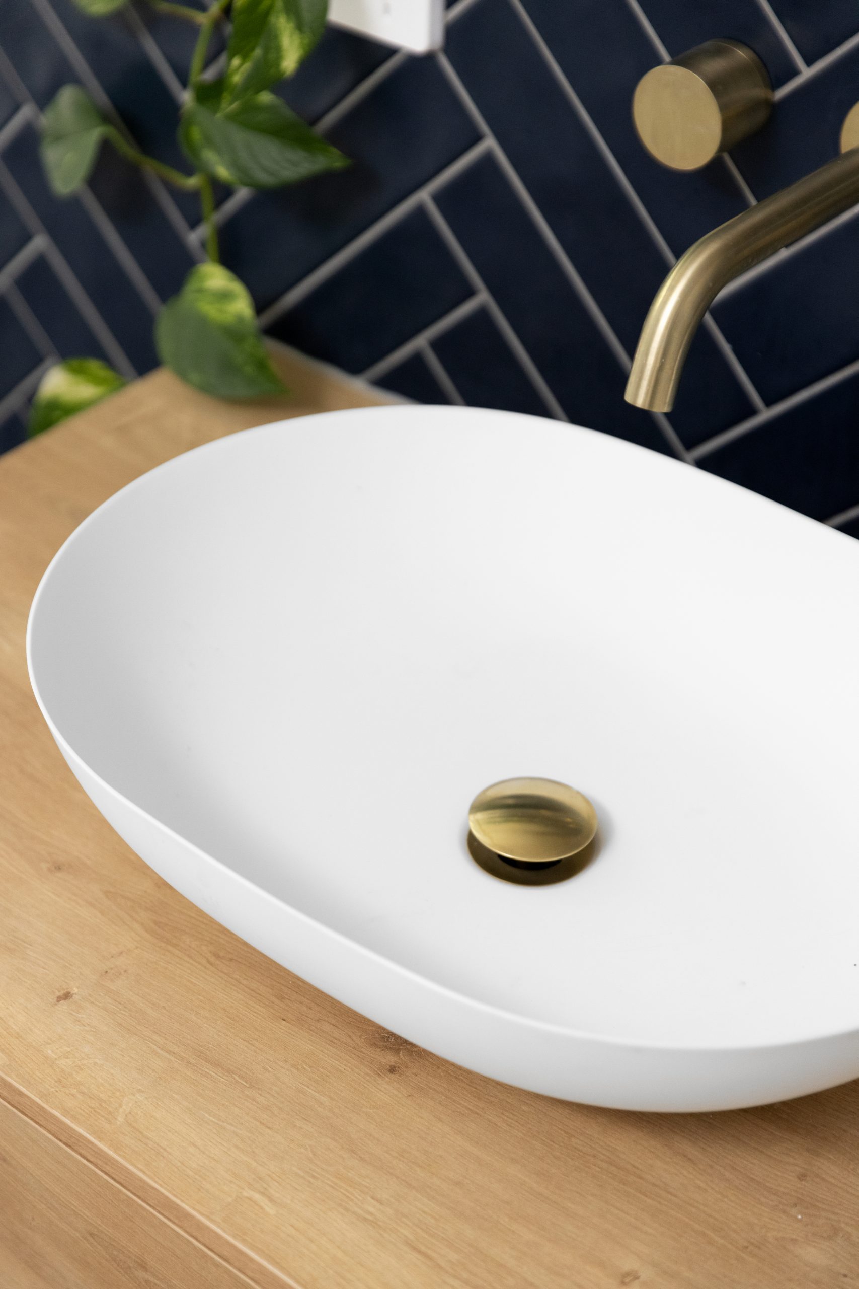 White sink on a wooden vanity with gold accessories