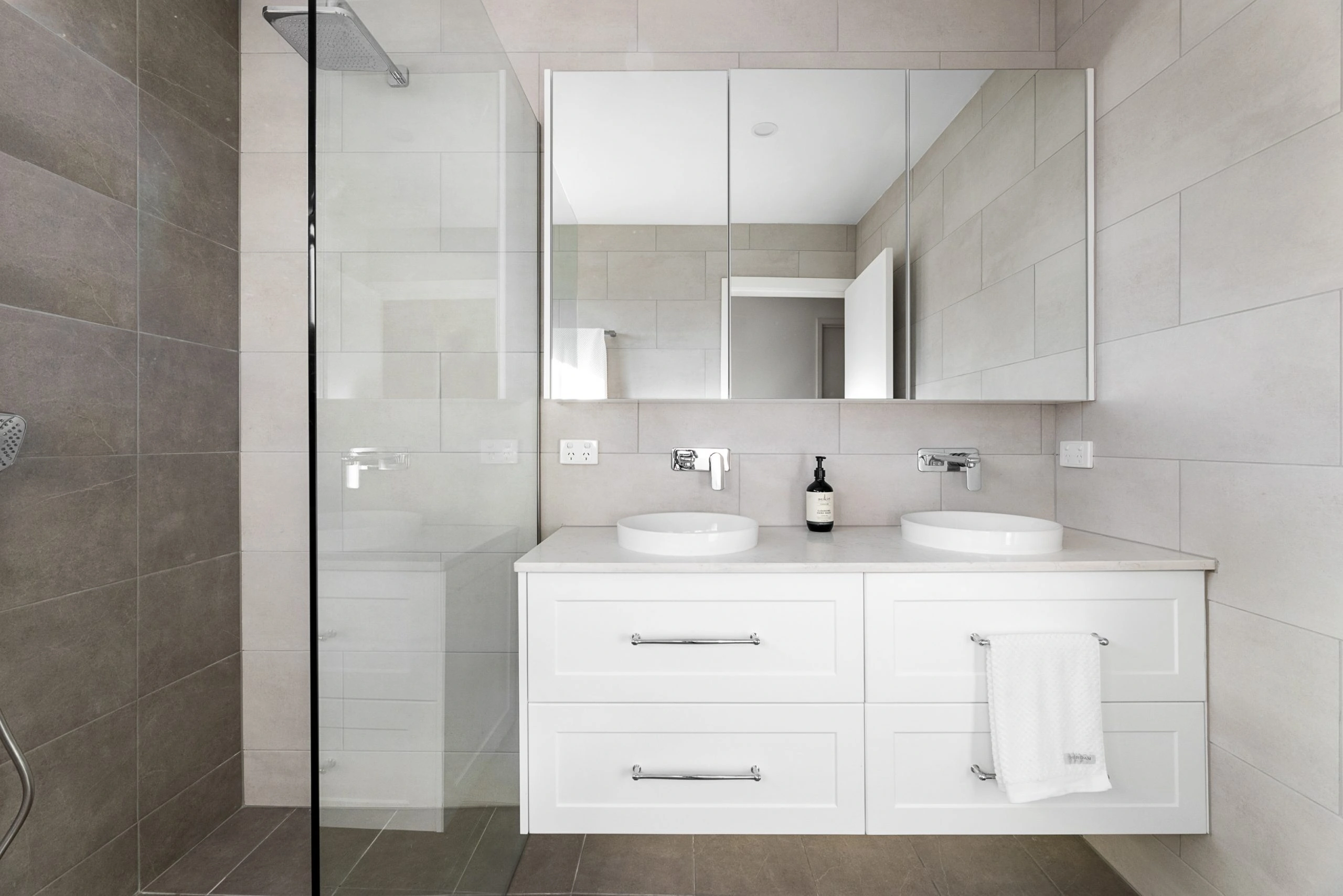White vanity unit with a mirrored bathroom wall unit above