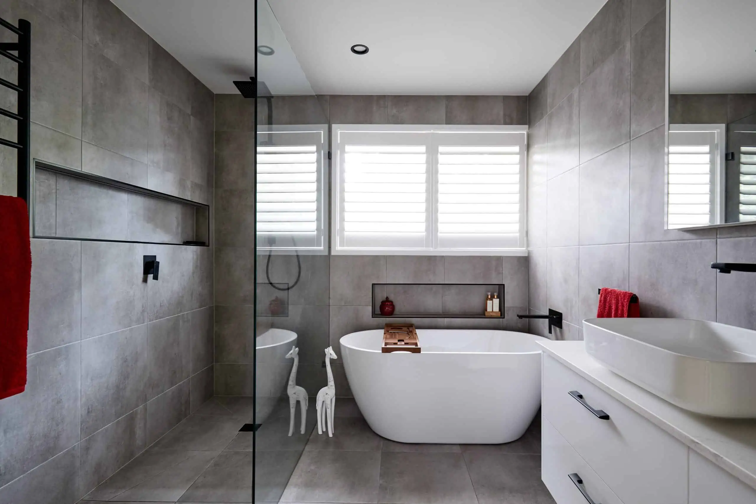 Grey bathroom with white bath and sink and black details