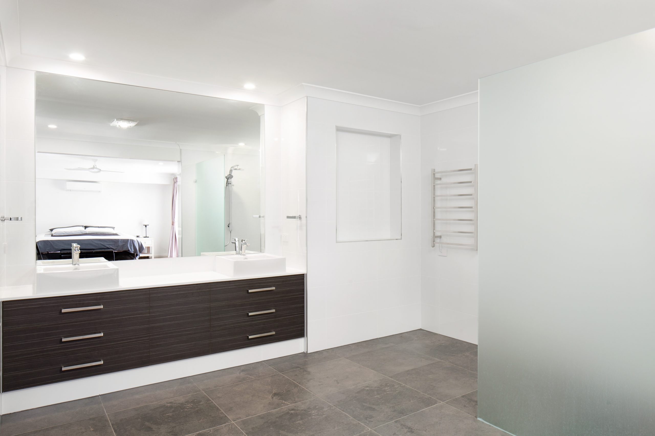 White bathroom with frosted glass shower screen and a large wall mirror