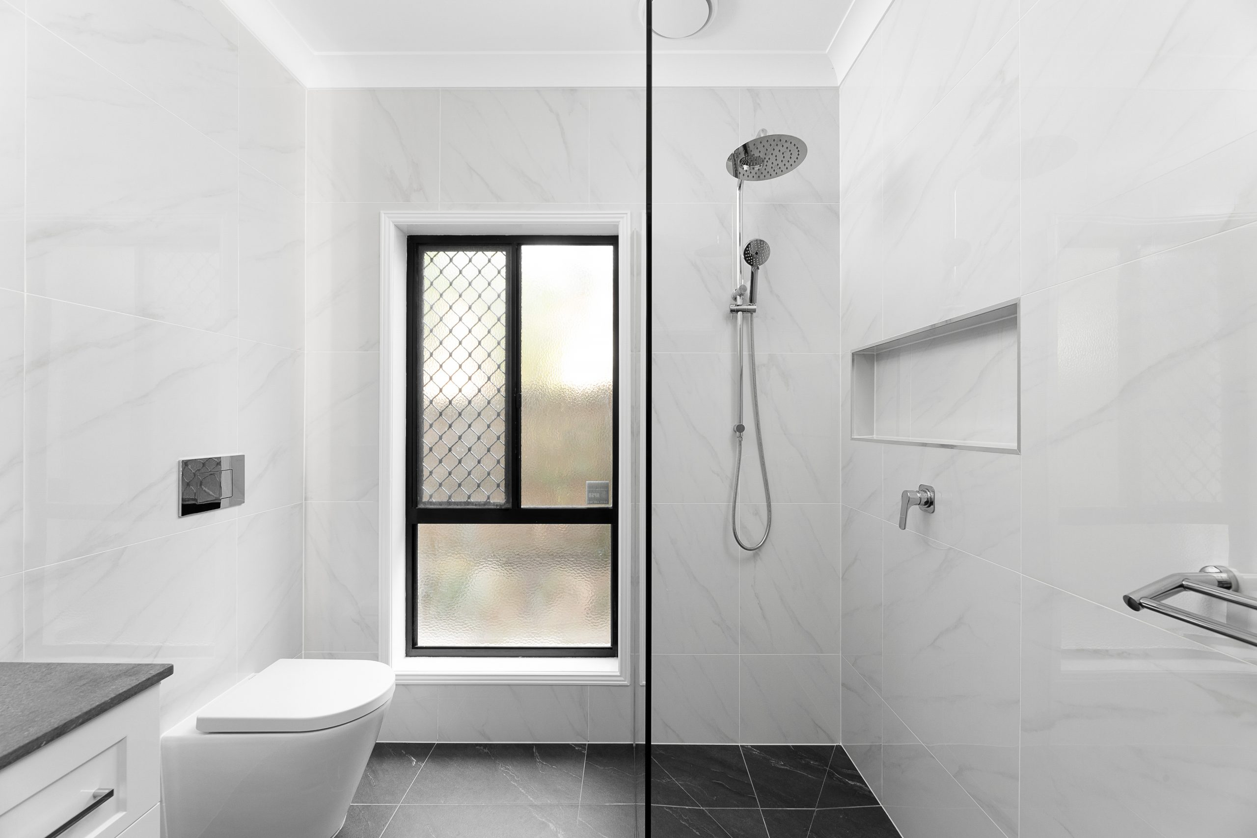 White bathroom with shower niche and chrome details