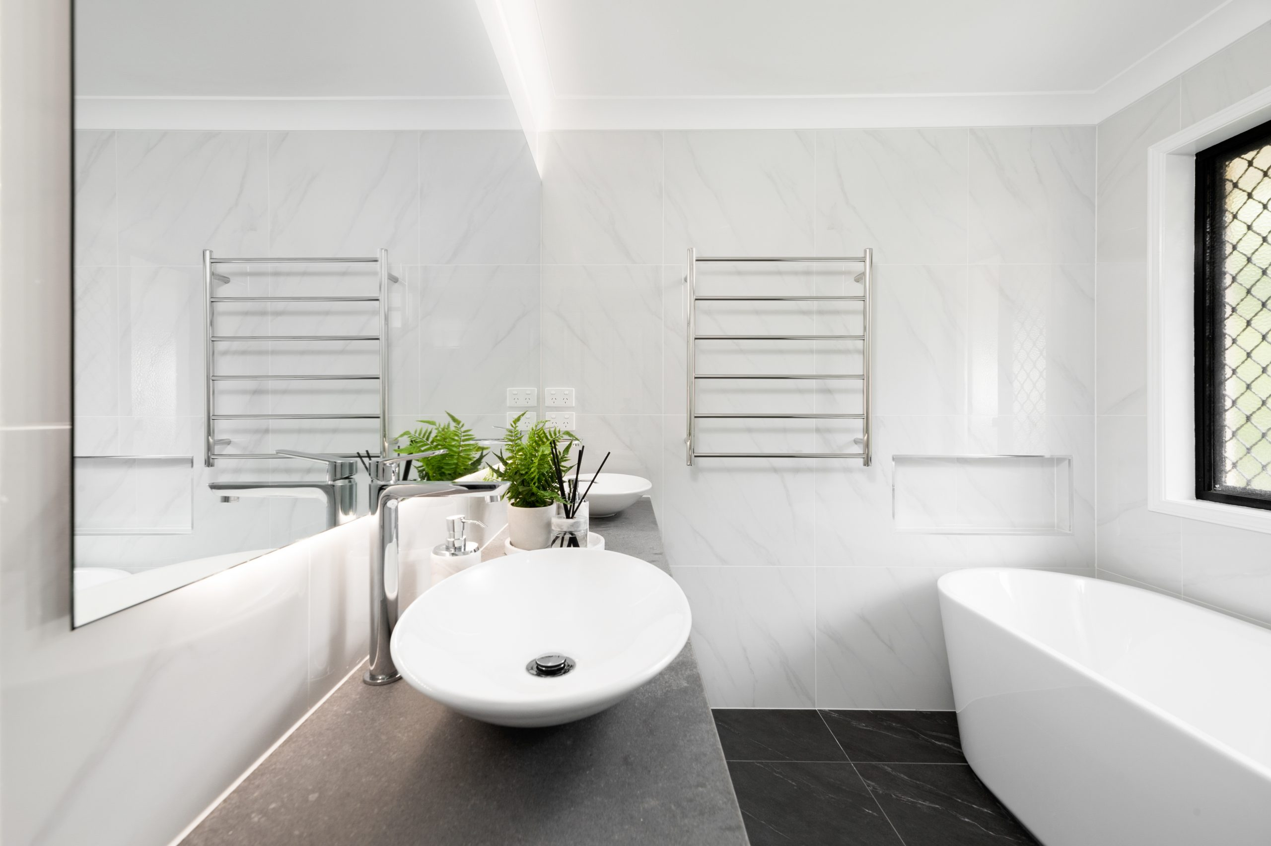 White bathroom aesthetic featuring a large wall mirror and chrome towel rail.