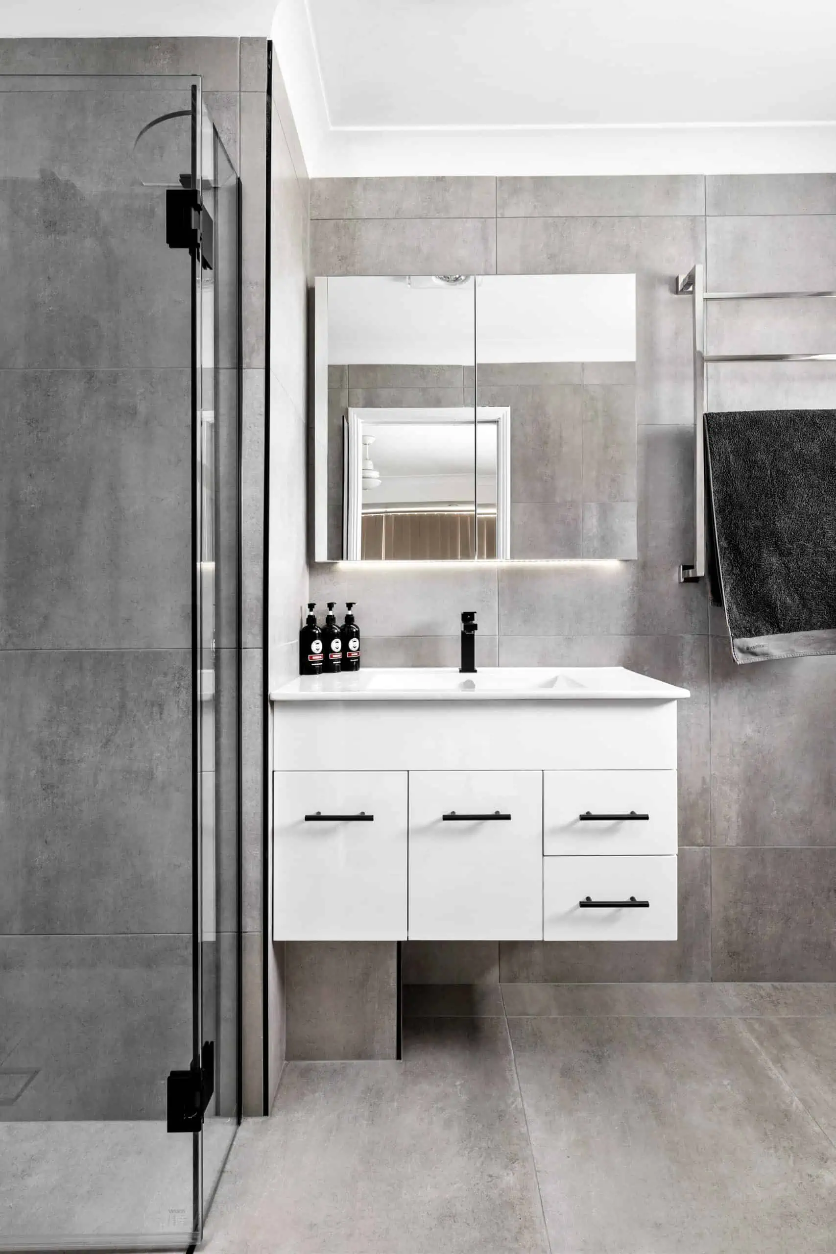White vanity unit in a modern bathroom with large wall and floor tiles