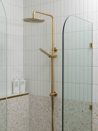 Gold shower with glass shower screen and white bathroom tiles