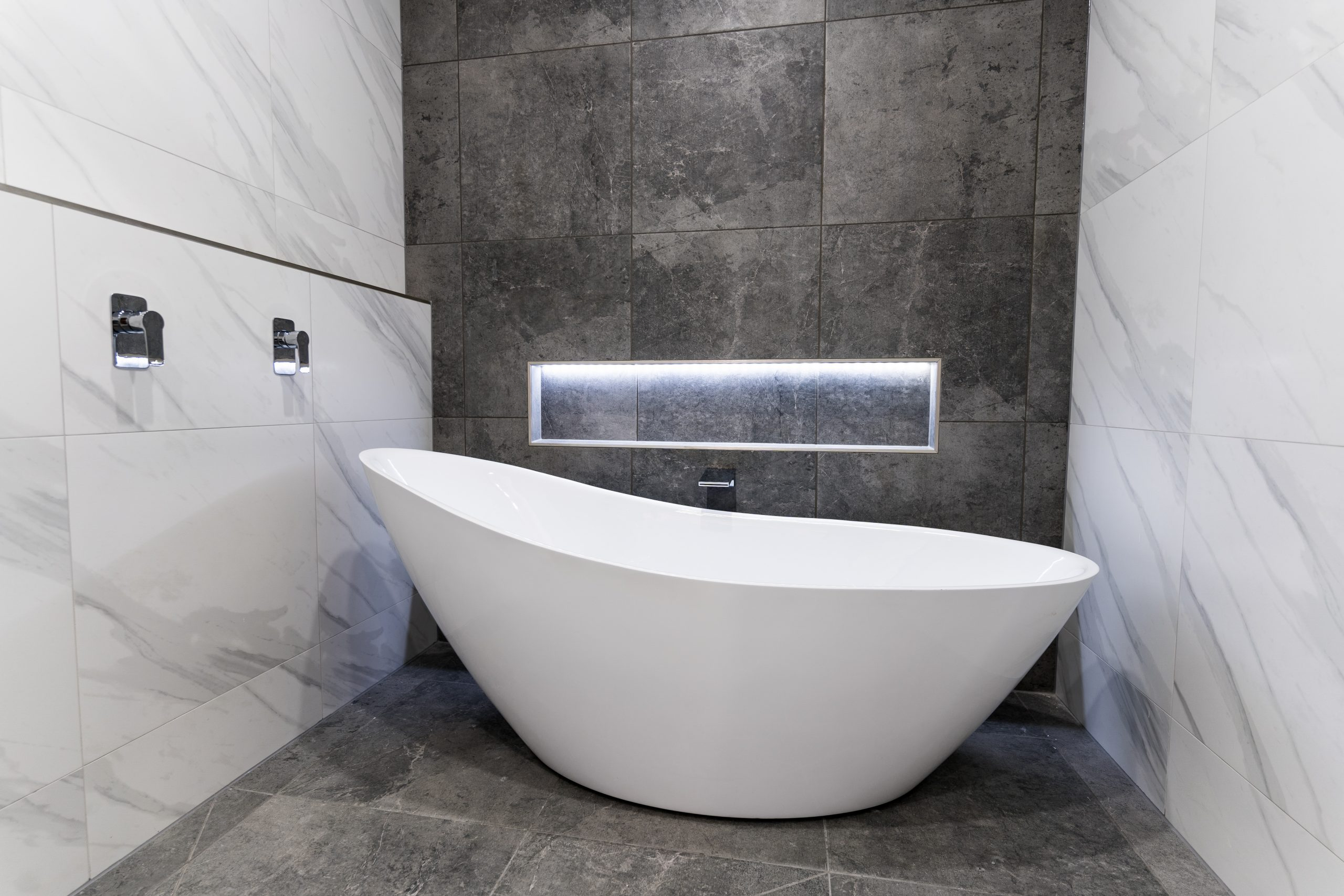 uniquely shaped bath in a modern bathroom with a wall niche