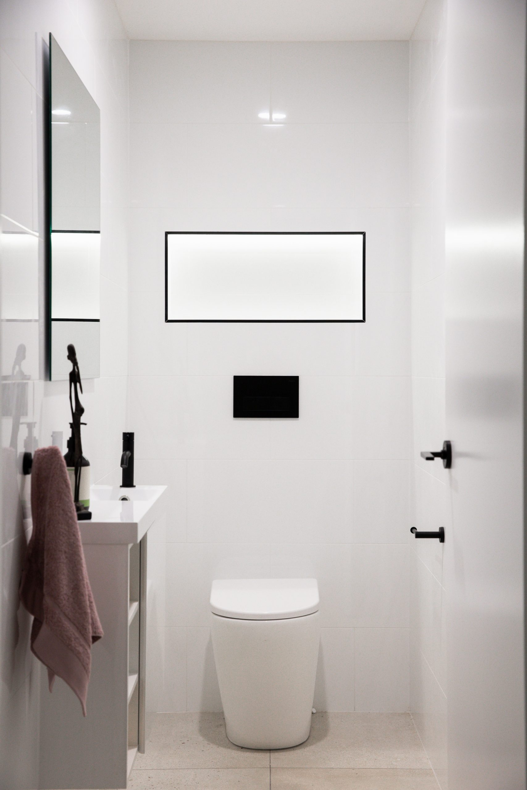 White bathroom with black details and a pink towel