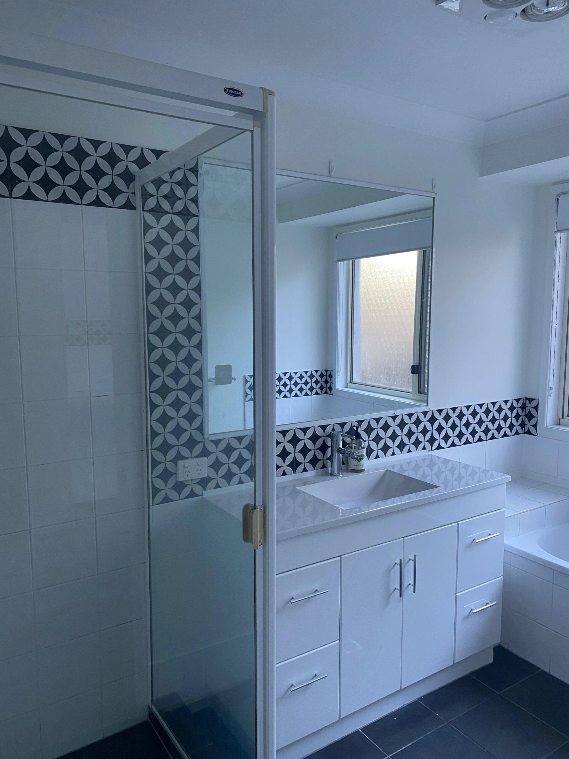 Before picture of a bathroom renovation, white units and blye patterned tiles.